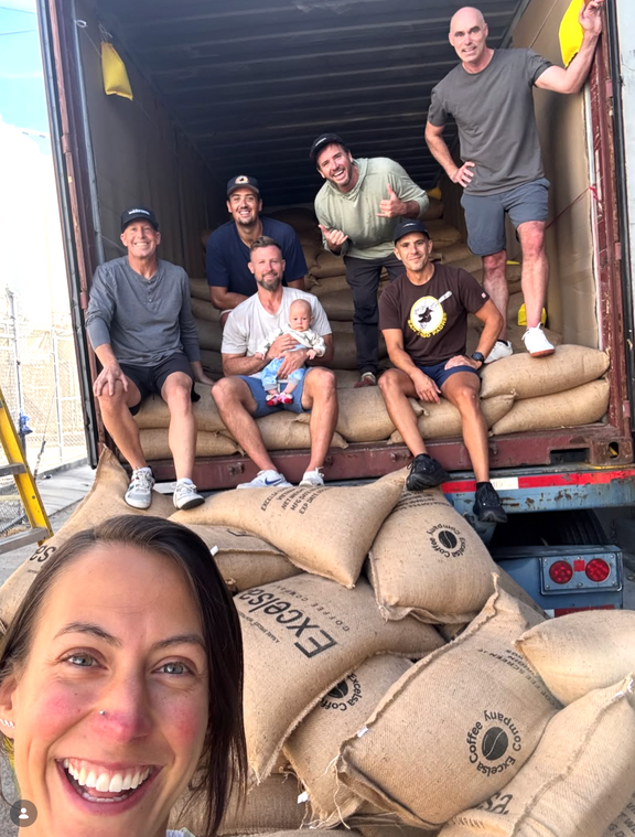 Excelsa Coffee team selfie with jute bags of green coffee loaded into a shipping container