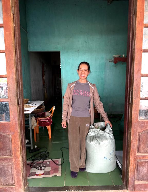 Smiling coffee producer holding a large sack of green coffee in a farmhouse doorway